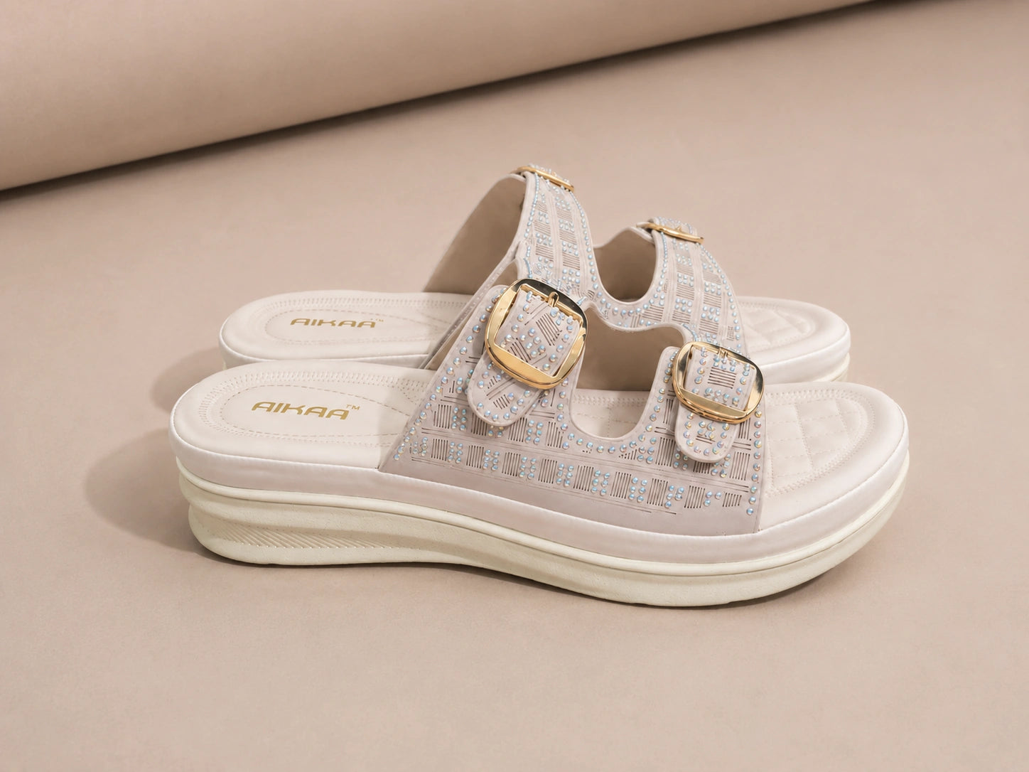 Pair of sandals with gold buckles on a beige background