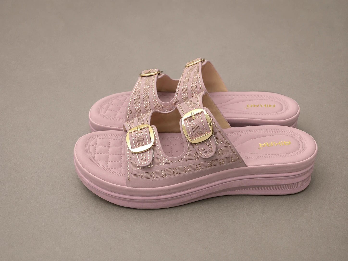 Pink jelly sandals with gold buckles on a gray background