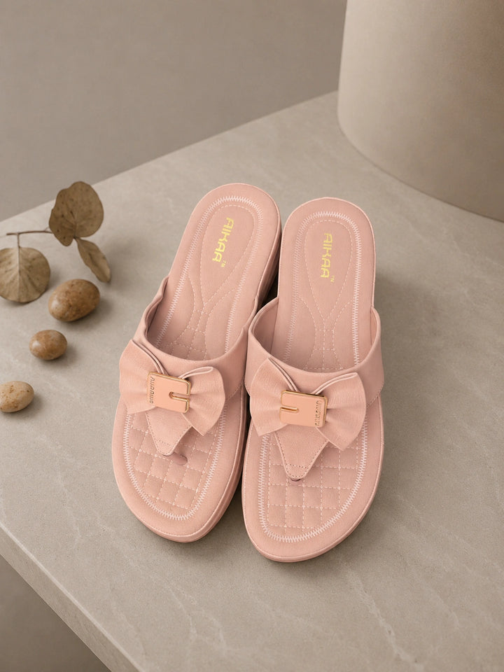 Pink slippers with bow details on a neutral background