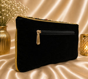 Black clutch bag with gold zipper on a beige fabric background