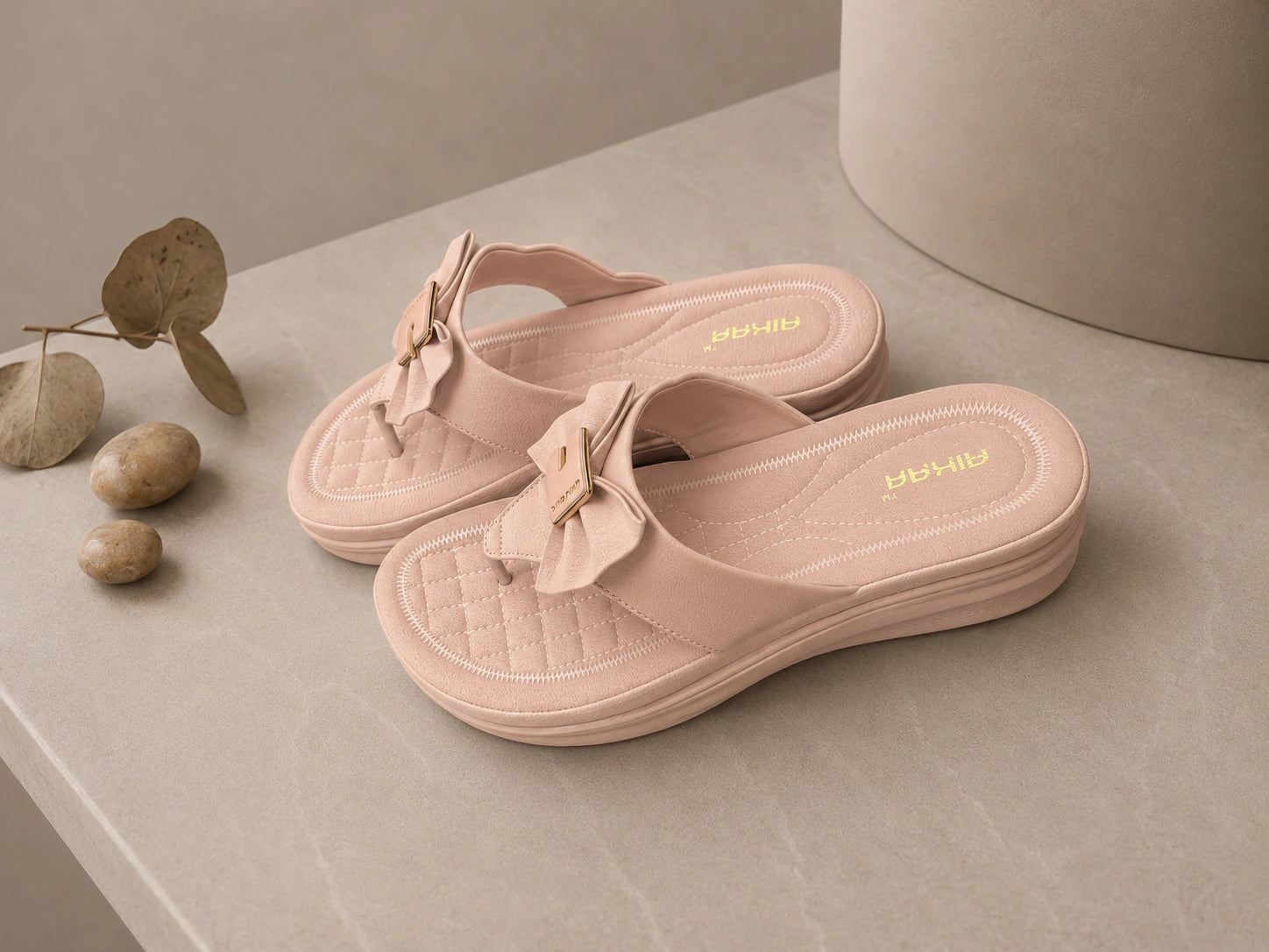 Pair of pink sandals with bow details on a neutral background