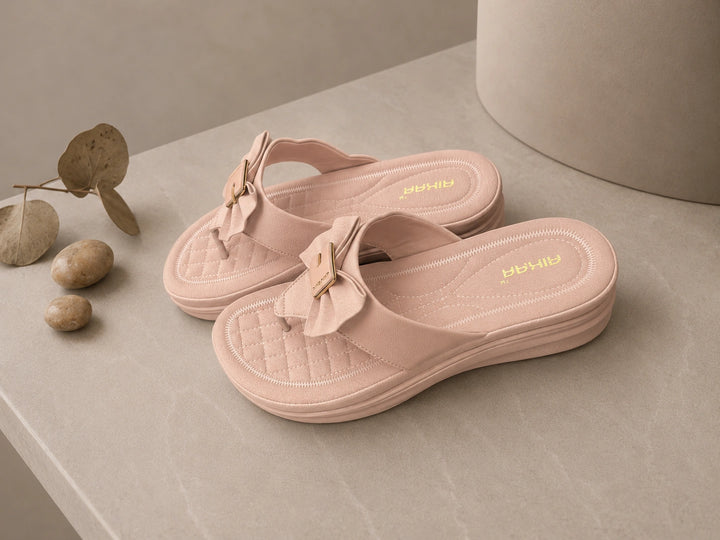 Pair of pink sandals with bow details on a neutral background