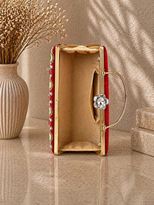 Red clutch with gold accents on a beige surface