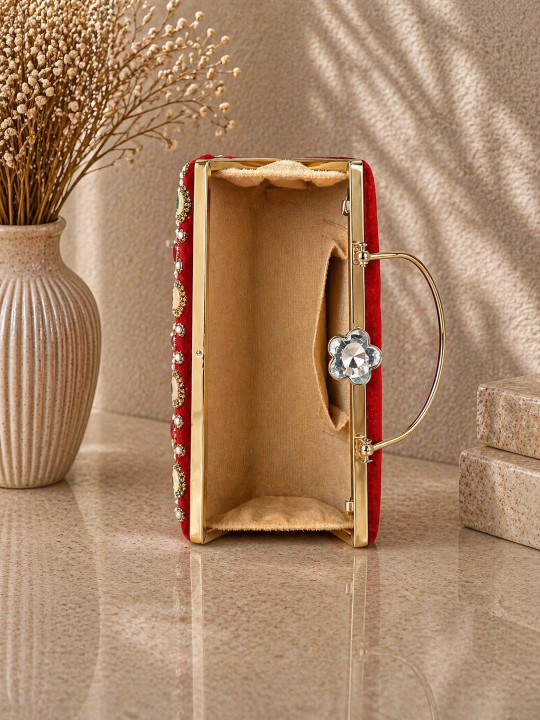 Red clutch with gold accents on a beige surface